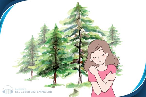 A girl hugging herself with evergreen trees in the background